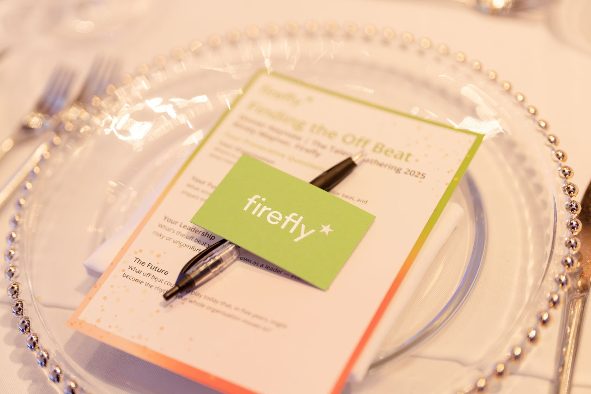A dinner plate with a Firefly brochure and postcard resting on a pen